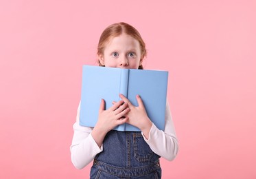 Photo of Cute little girl with books on pink background