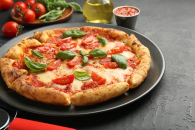Photo of Delicious Margherita pizza and ingredients on black table