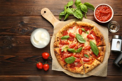 Photo of Delicious Margherita pizza and ingredients on wooden table, top view