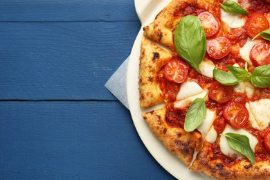 Photo of Delicious Margherita pizza on blue wooden table, top view. Space for text