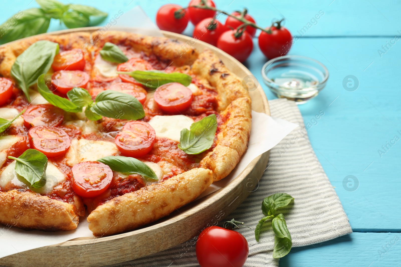 Photo of Delicious Margherita pizza and ingredients on light blue wooden table