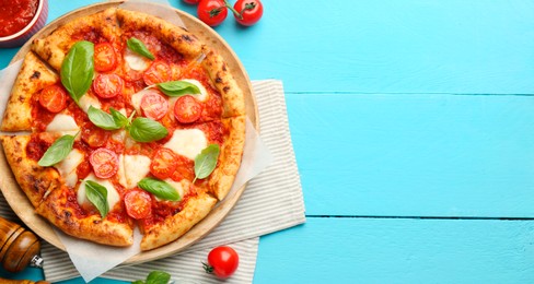 Photo of Delicious Margherita pizza and ingredients on light blue wooden table, top view. Space for text