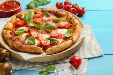 Photo of Delicious Margherita pizza and ingredients on light blue wooden table