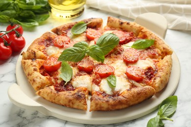 Photo of Delicious Margherita pizza and ingredients on white marble table