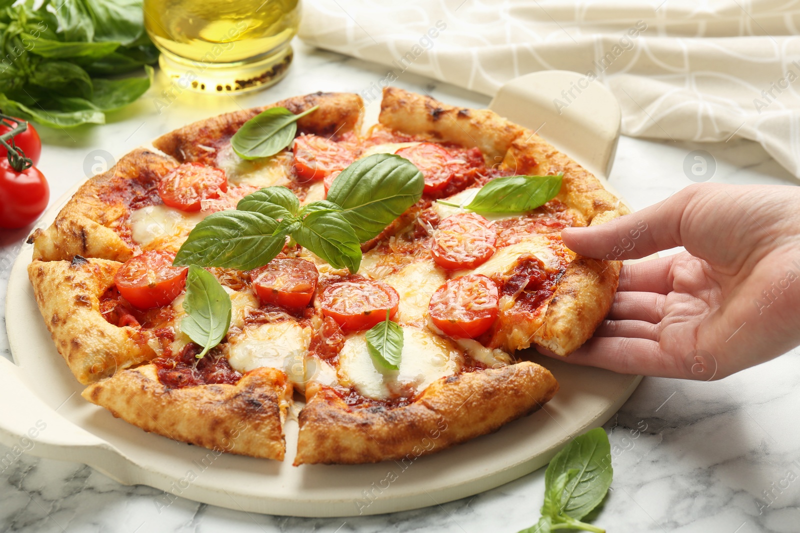 Photo of Woman taking piece of delicious Margherita pizza at white marble table, closeup