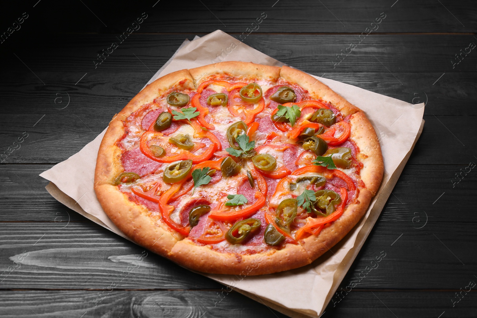 Photo of Delicious pizza Diablo on black wooden table