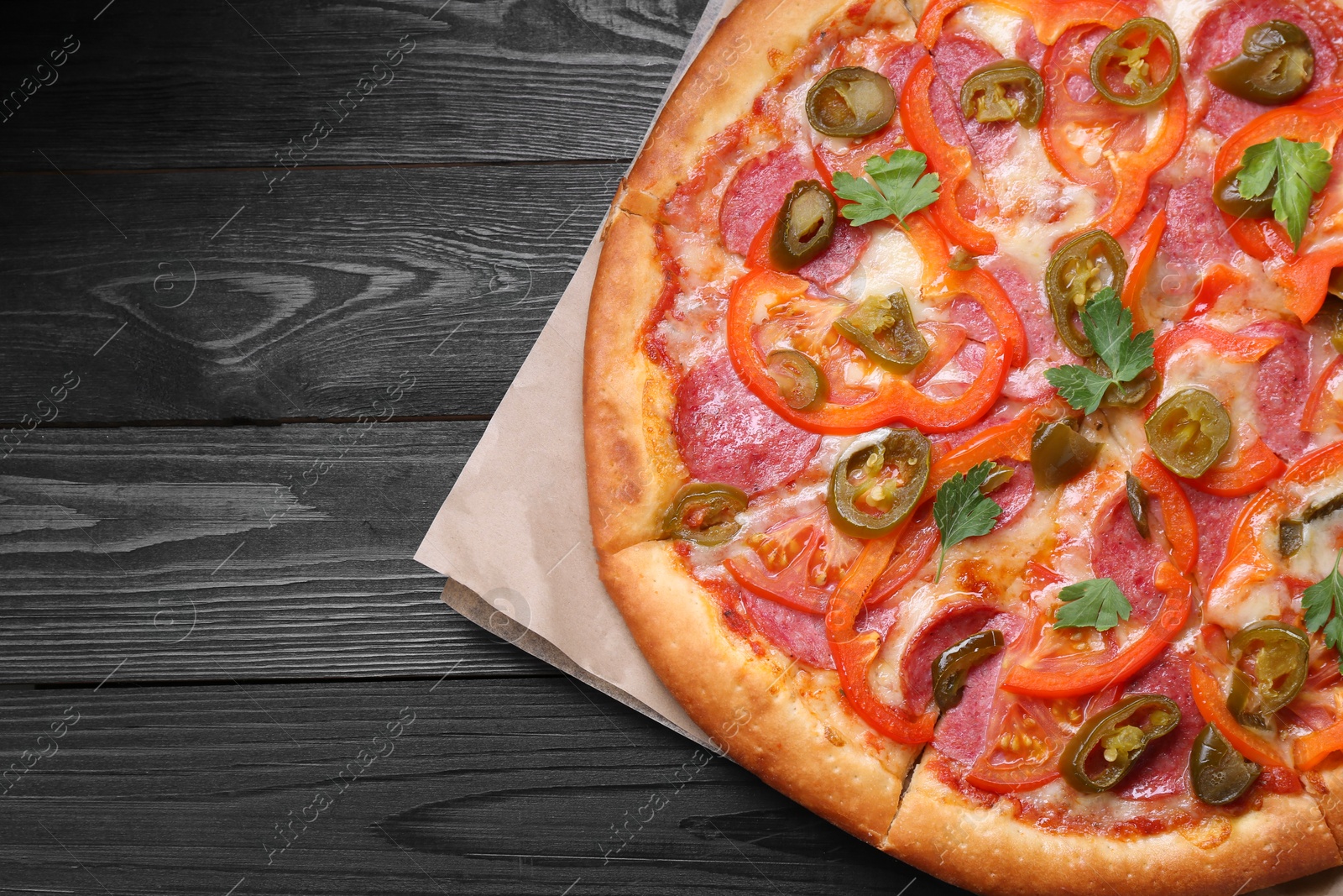 Photo of Delicious pizza Diablo on black wooden table, top view. Space for text