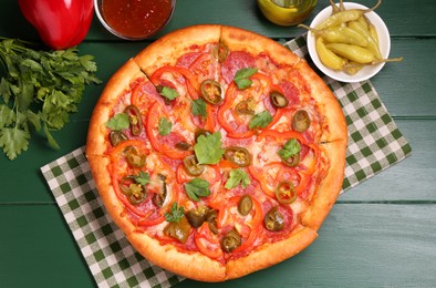 Photo of Delicious pizza Diablo and ingredients on green wooden table, flat lay