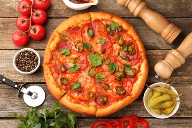 Photo of Delicious pizza Diablo, ingredients and cutter on wooden table, flat lay