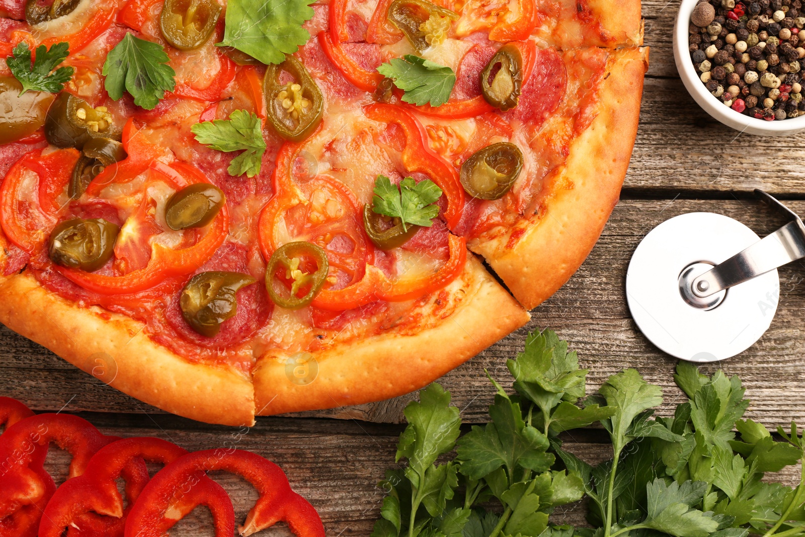 Photo of Delicious pizza Diablo, ingredients and cutter on wooden table, flat lay