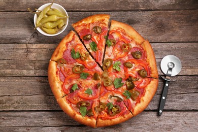 Photo of Delicious pizza Diablo, pickled peppers and cutter on wooden table, flat lay