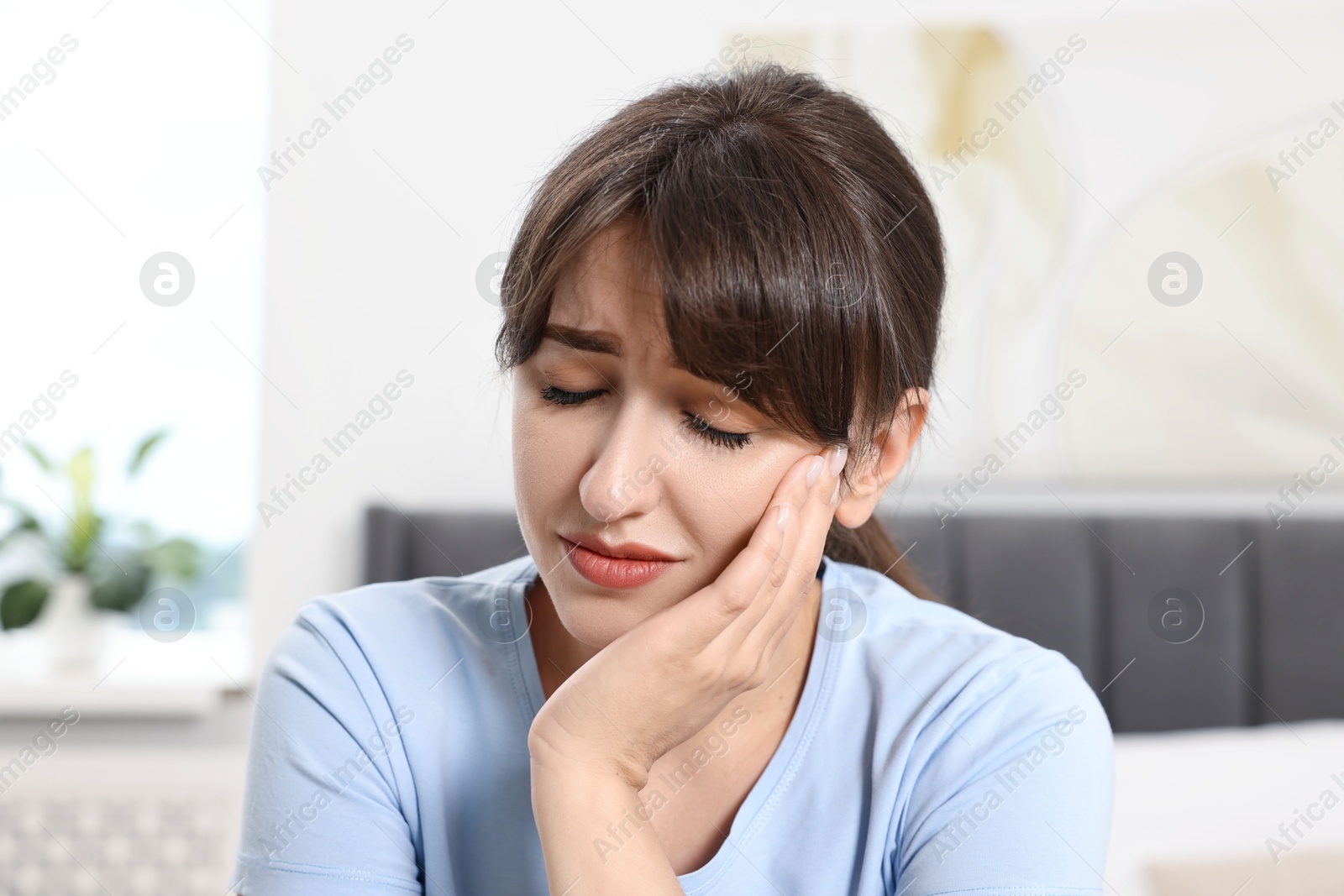 Photo of Upset young woman suffering from toothache indoors