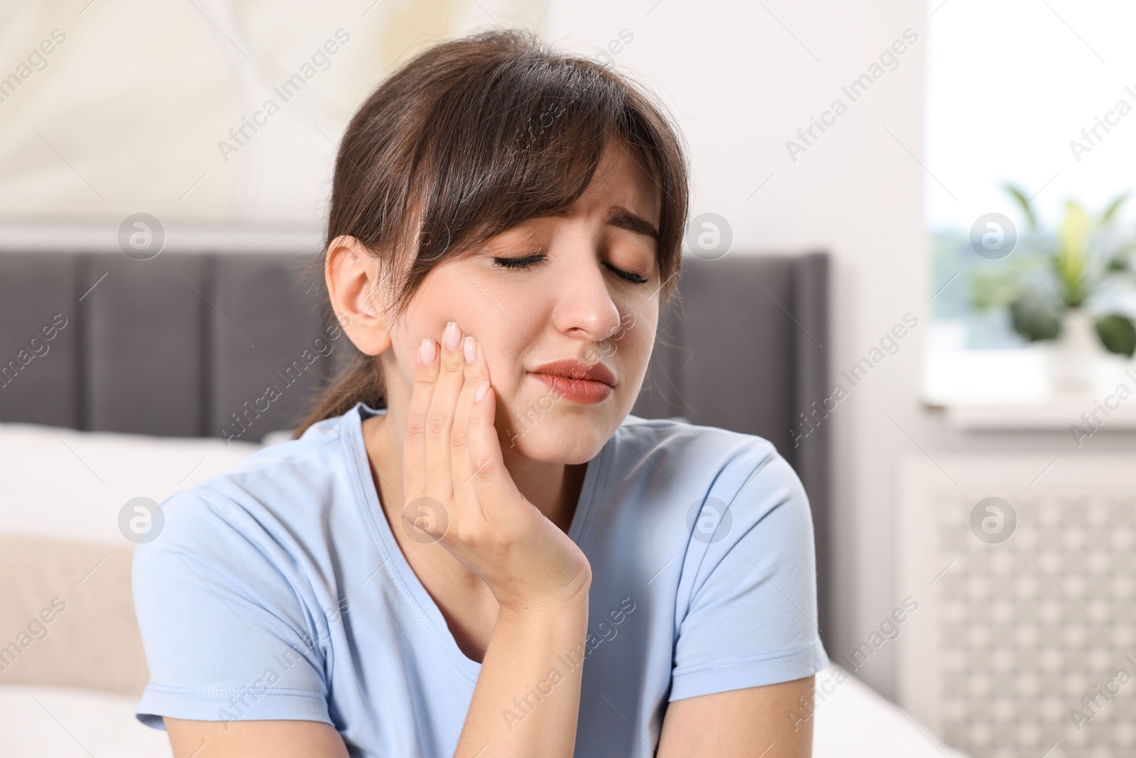 Photo of Upset young woman suffering from toothache indoors