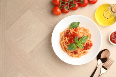 Photo of Delicious pasta with tomato sauce and basil in bowl on wooden table, flat lay. Space for text