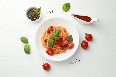 Photo of Delicious pasta with tomato sauce, peppercorns, vegetables and basil on white wooden table, flat lay