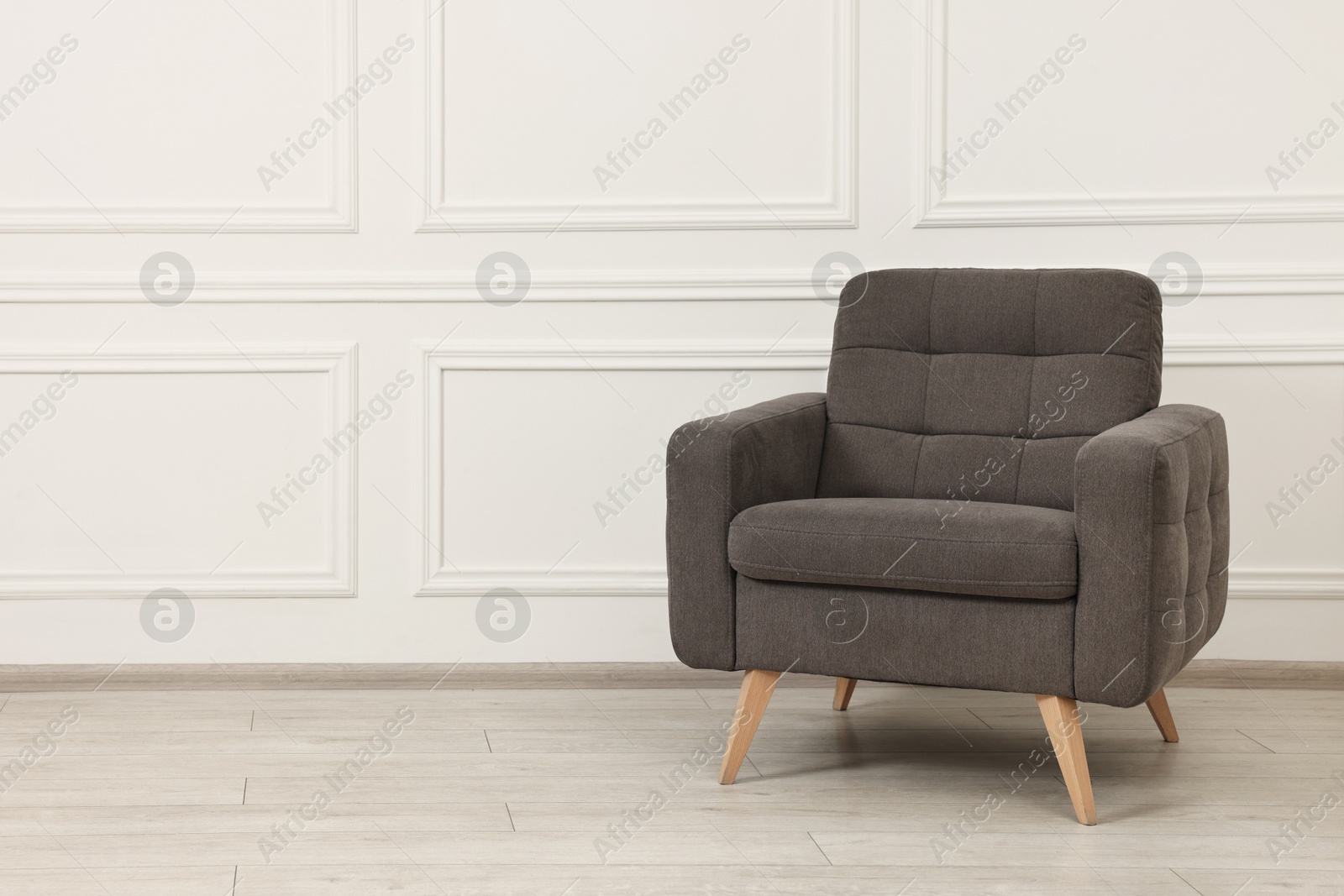 Photo of One soft armchair near white wall indoors. Space for text