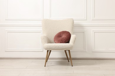 Soft armchair with pillow in light room