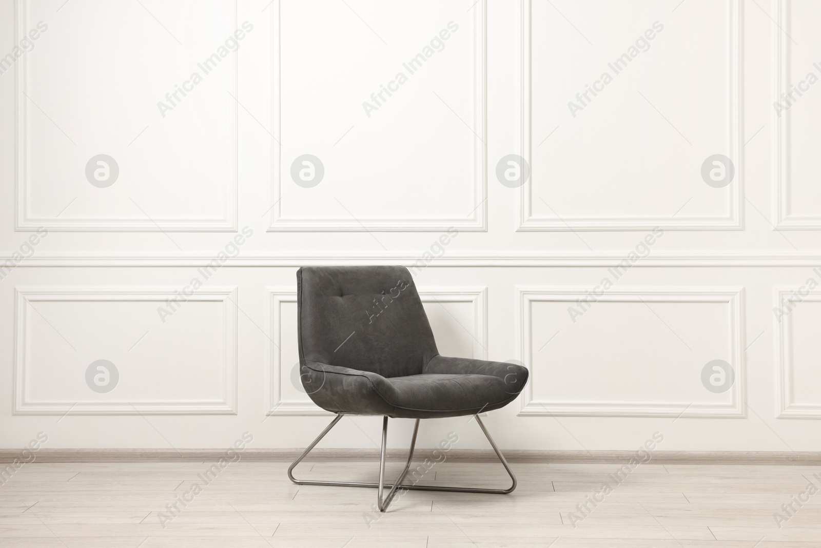 Photo of One soft armchair near white wall indoors