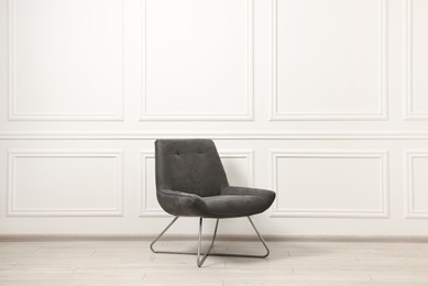 One soft armchair near white wall indoors