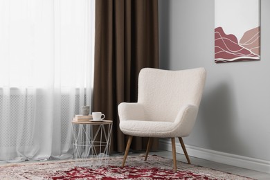 Photo of Soft armchair, side table and window with curtains indoors. Interior design