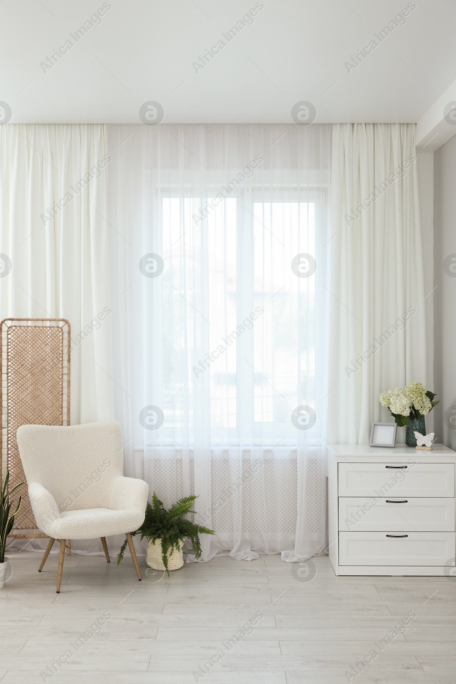 Photo of Soft armchair, chest of drawers, houseplant and window with curtains in room. Interior design