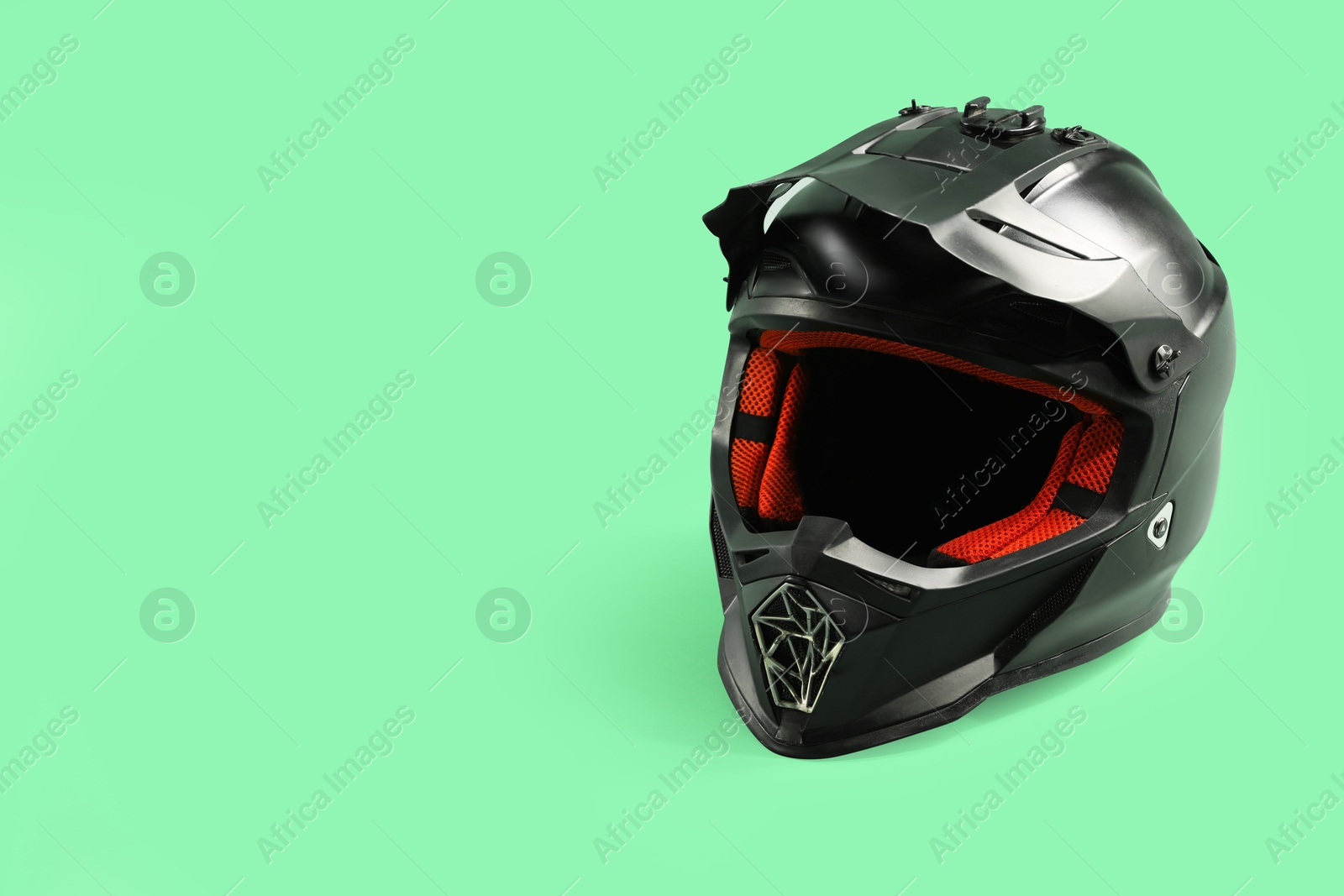 Photo of Modern motorcycle helmet with visor on light green background. Space for text