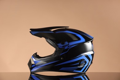 Photo of Modern motorcycle helmet with visor on mirror surface against beige background