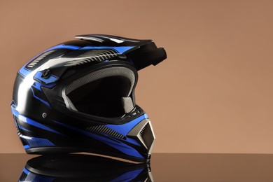 Photo of Modern motorcycle helmet with visor on mirror surface against beige background. Space for text