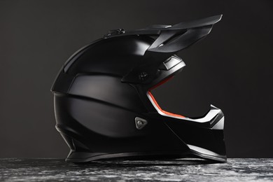 Photo of Modern motorcycle helmet with visor on grey stone surface against black background