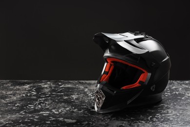 Photo of Modern motorcycle helmet with visor on grey stone surface against black background. Space for text