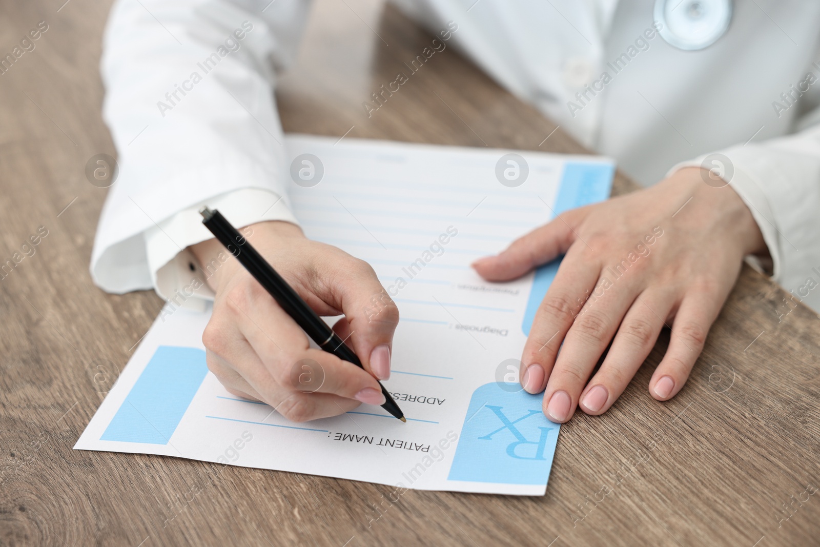 Photo of Doctor writing prescription at wooden table in clinic, closeup