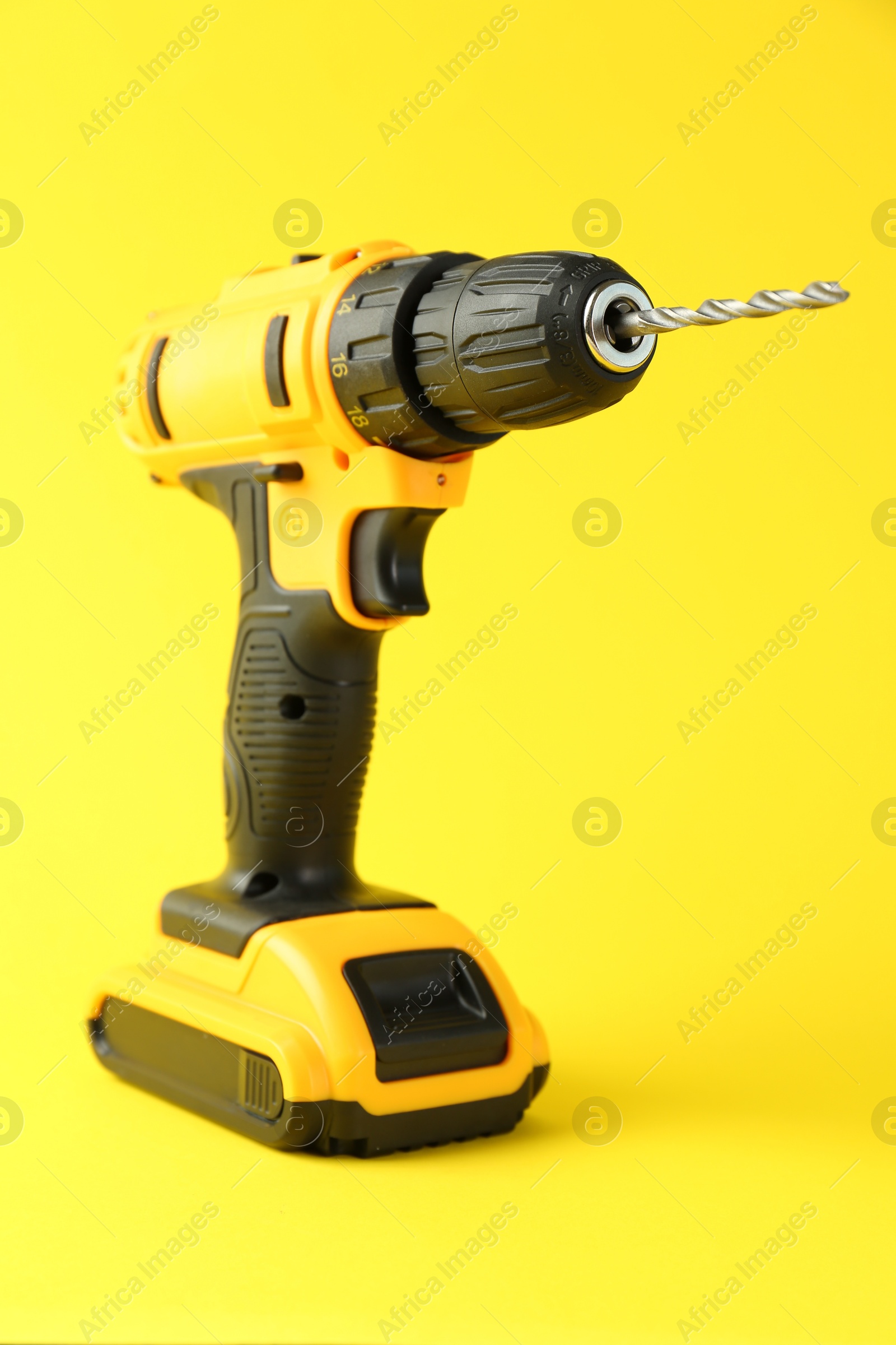 Photo of Modern cordless electric drill on yellow background