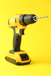 Modern cordless electric drill on yellow background