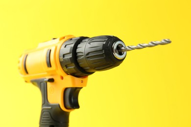 Modern cordless electric drill on yellow background, closeup