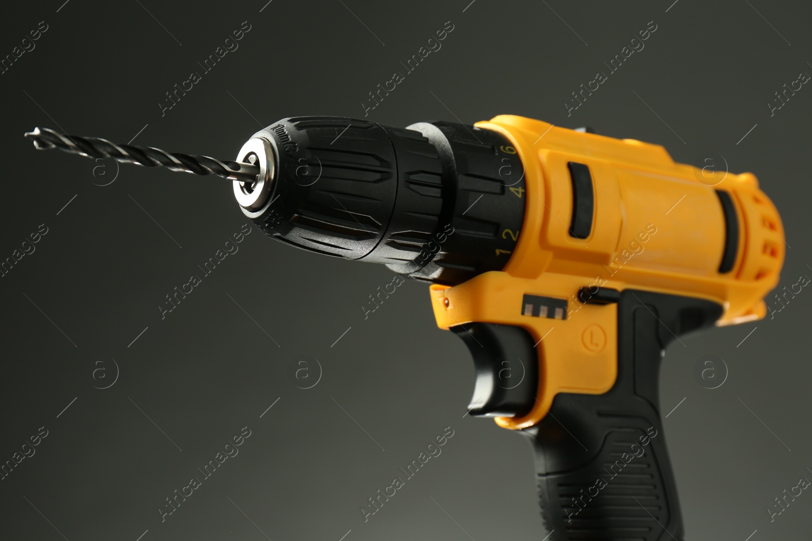 Photo of Modern cordless electric drill on grey background, closeup