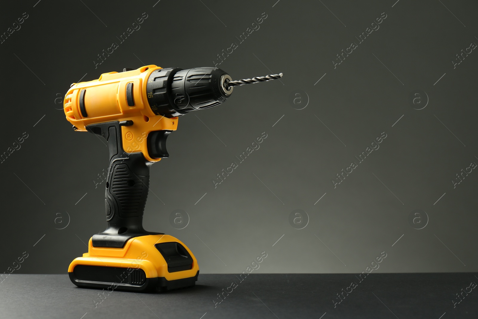 Photo of Modern cordless electric drill on grey background. Space for text