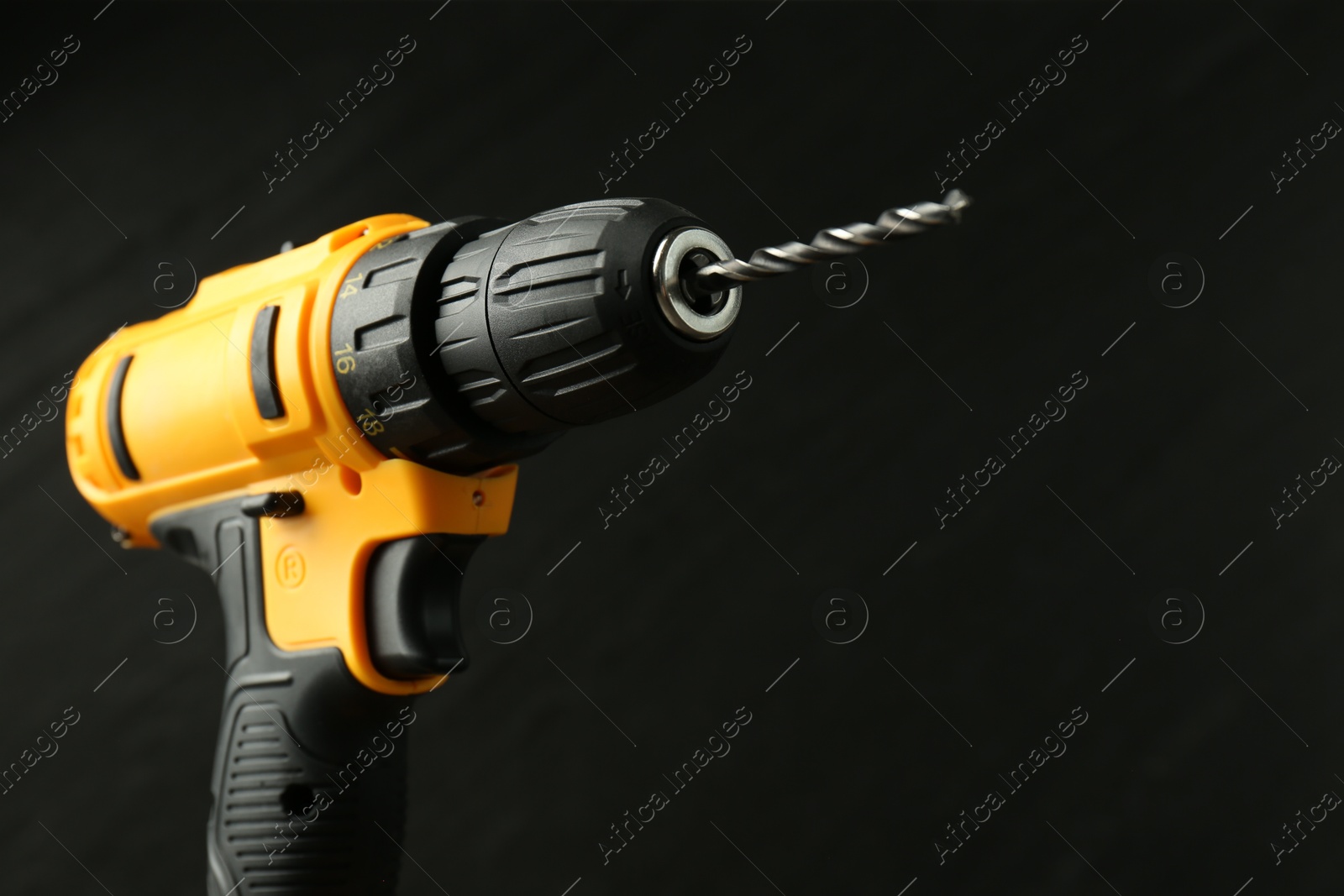 Photo of Modern cordless electric drill on black background, closeup