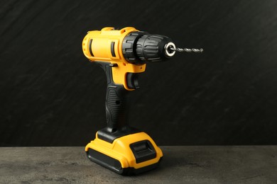 Modern cordless electric drill on grey table against black background