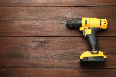 Photo of Modern cordless electric drill on wooden table, top view. Space for text