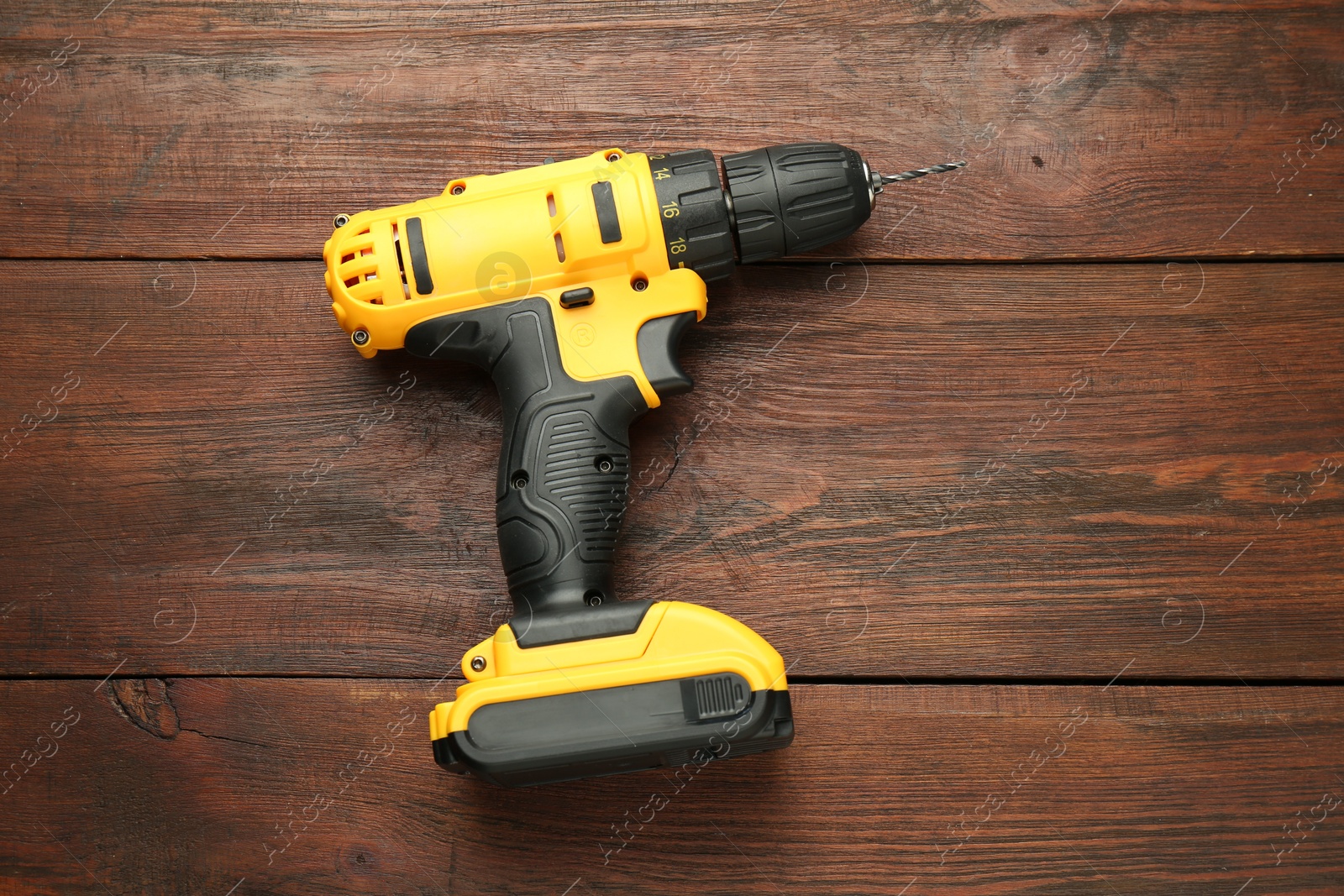 Photo of Modern cordless electric drill on wooden table, top view