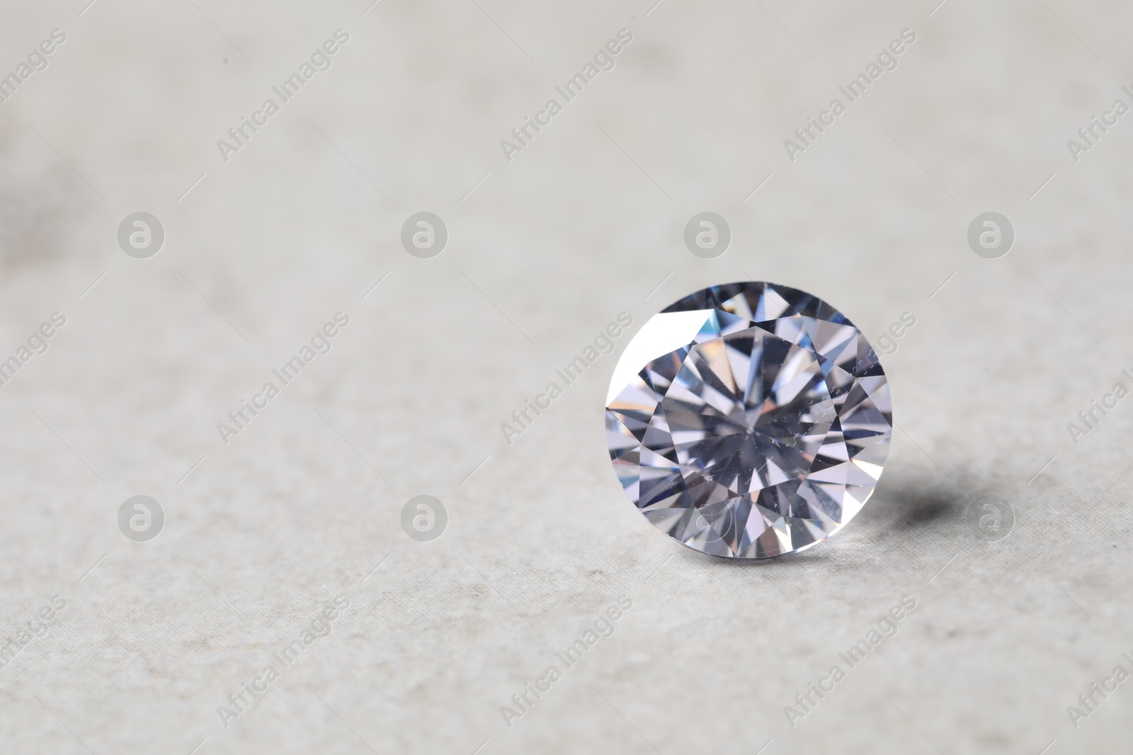 Photo of One beautiful shiny diamond on light background, closeup. Space for text