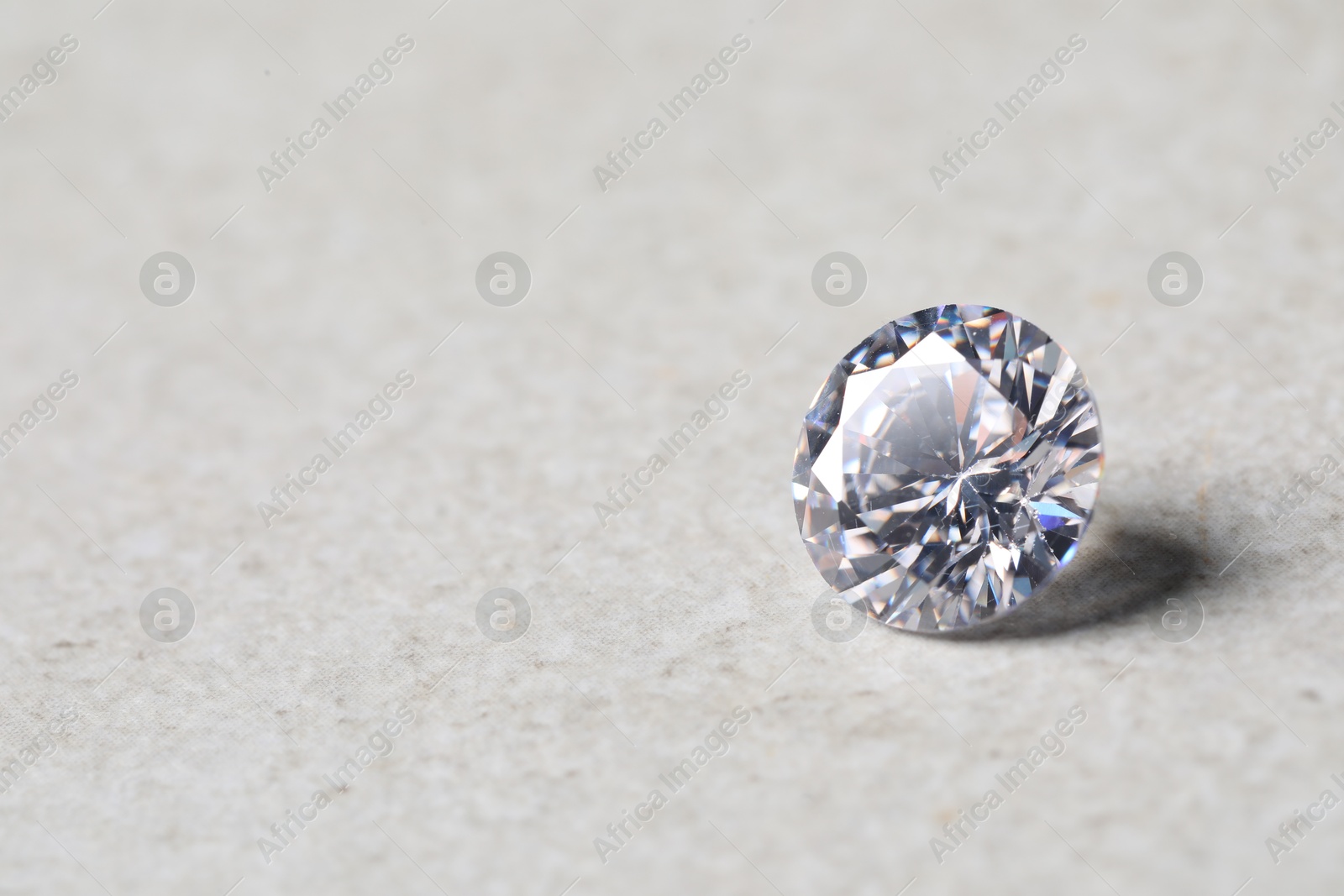 Photo of One beautiful shiny diamond on light background, closeup. Space for text