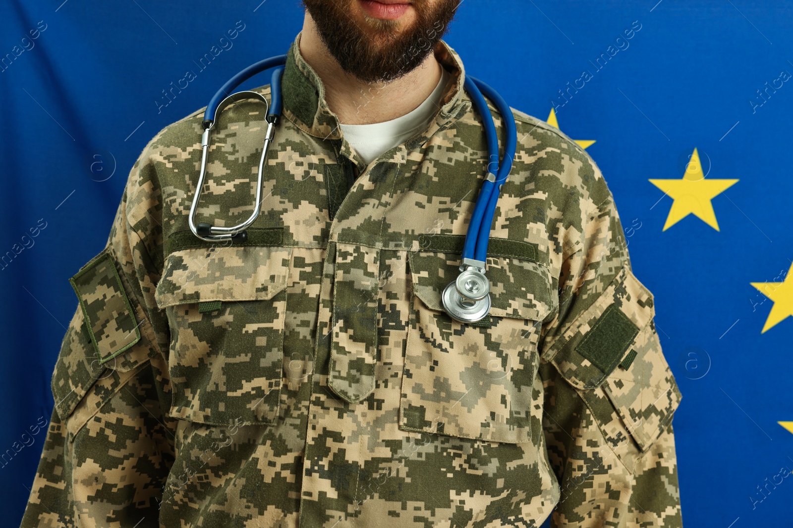 Photo of Man in military uniform with stethoscope against flag of European Union, closeup. Health care concept