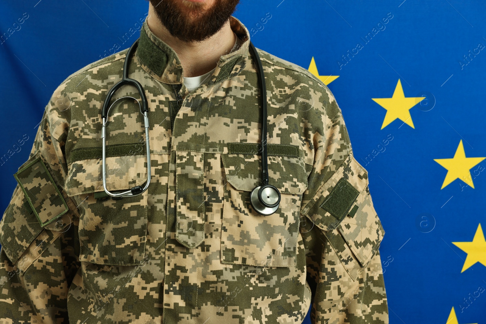 Photo of Man in military uniform with stethoscope against flag of European Union, closeup. Health care concept