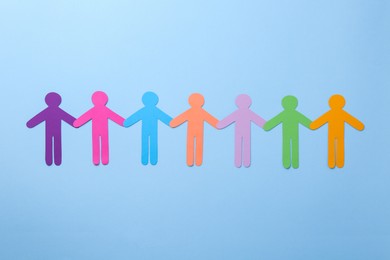 Photo of Equality concept. Different human figures on light blue background, flat lay