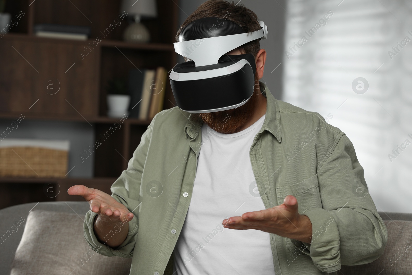 Photo of Man using virtual reality headset on sofa at home