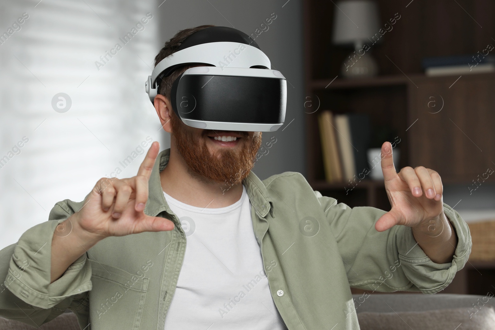 Photo of Man using virtual reality headset on sofa at home