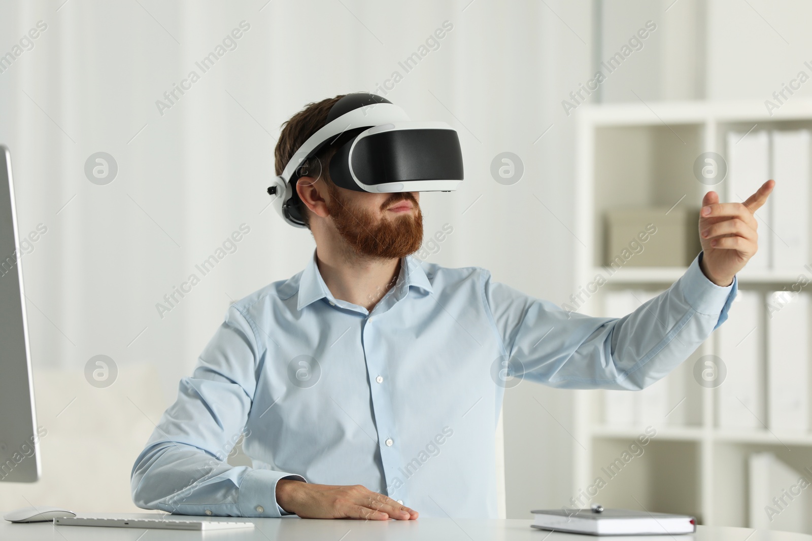 Photo of Man using virtual reality headset at workplace in office