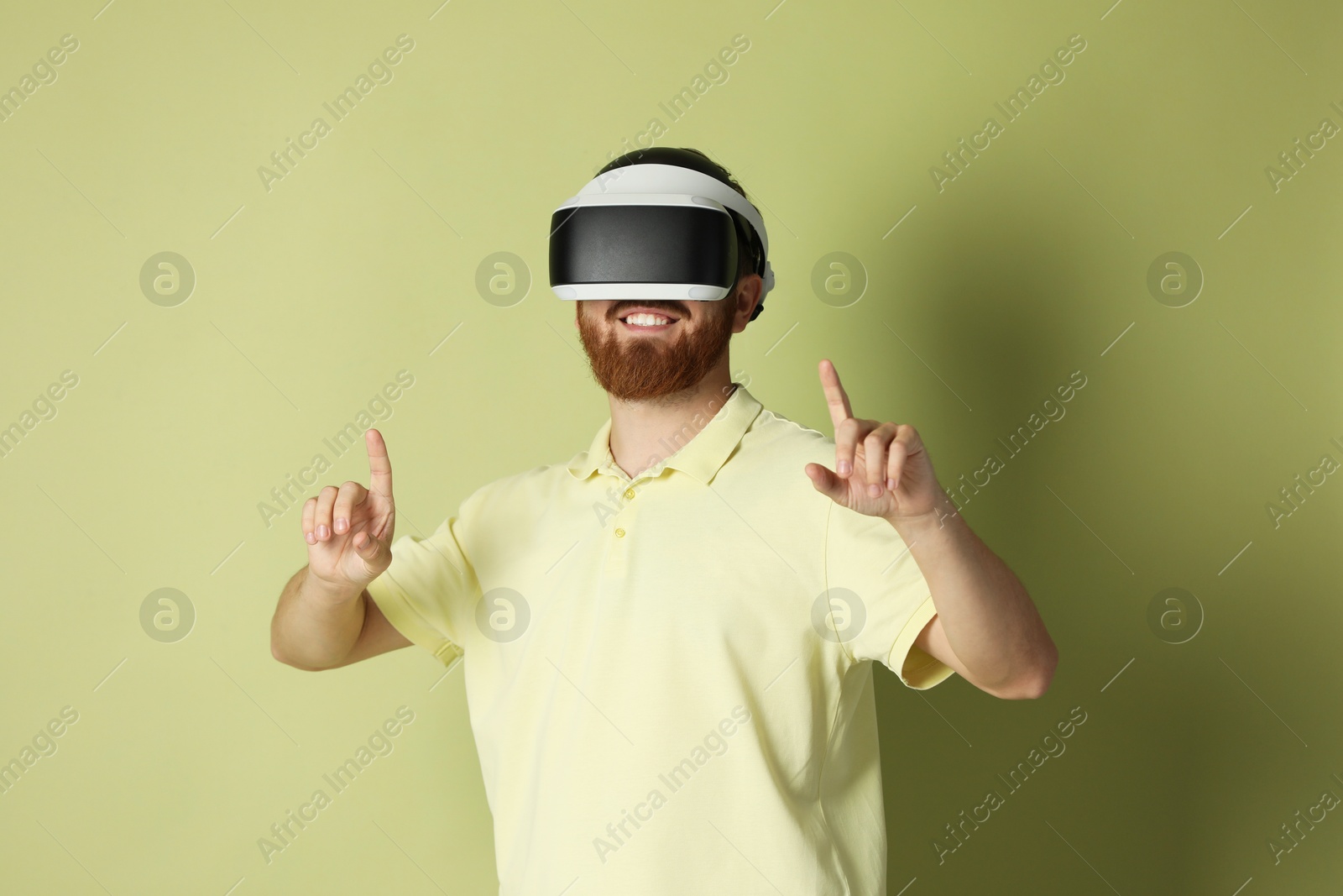 Photo of Smiling man using virtual reality headset on pale green background