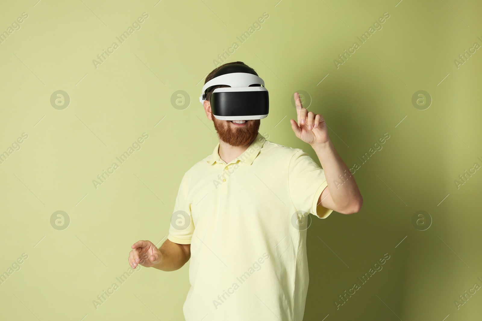 Photo of Smiling man using virtual reality headset on pale green background